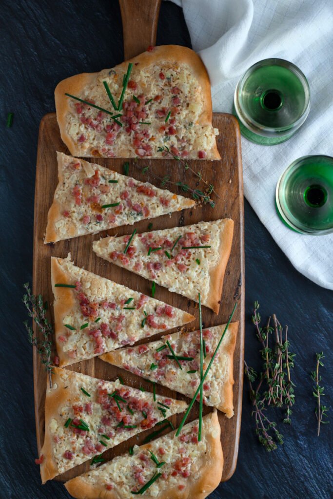 Flammkuchen German Pizza on a wooden board with two glasses of wine