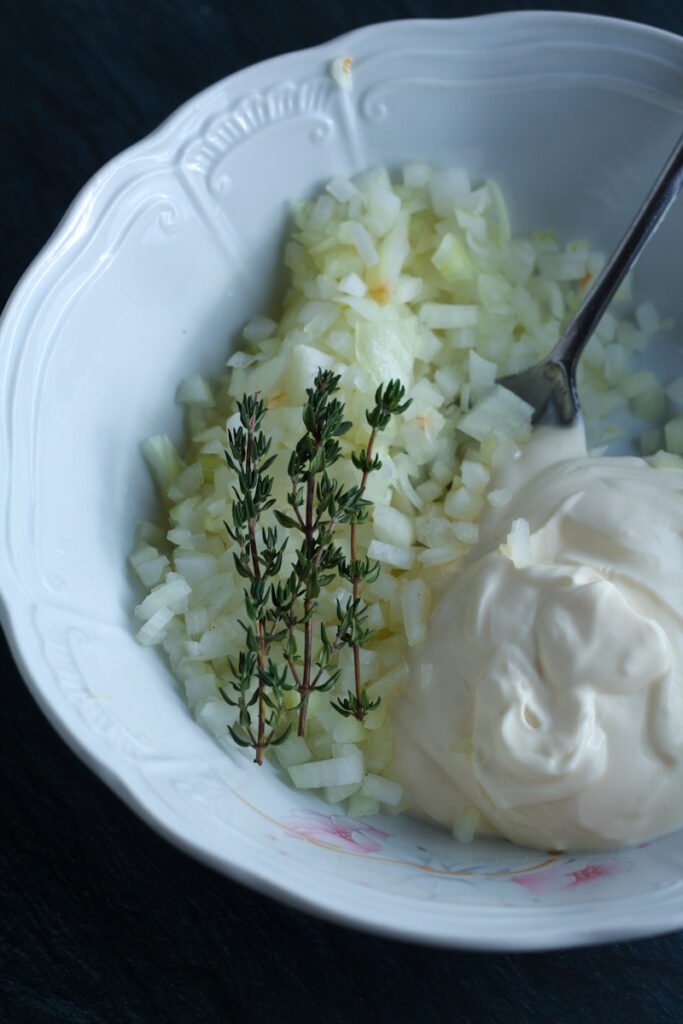 Diced onion, creme fraiche and thyme in a bowl for flammkuchen german pizza