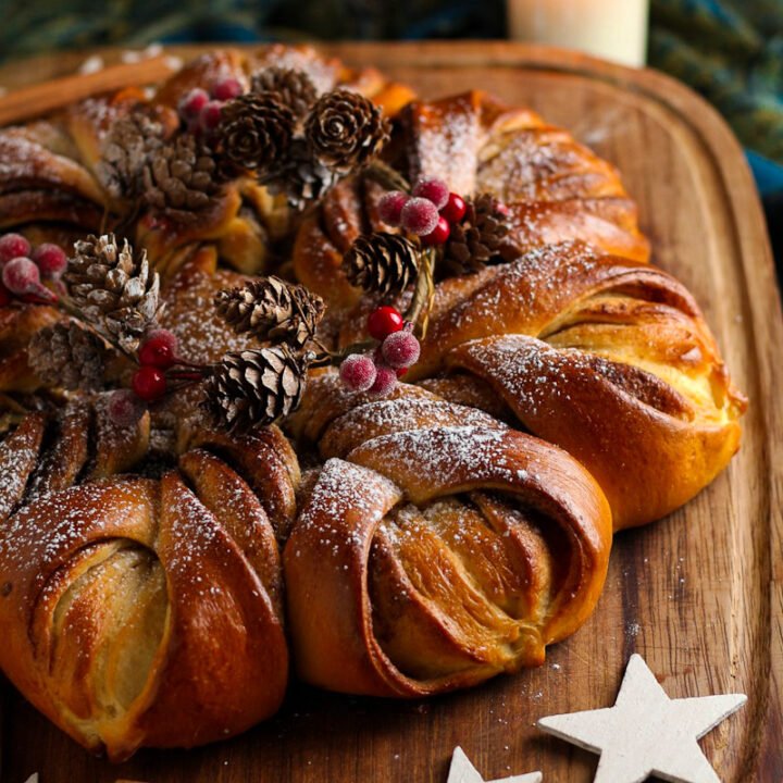 Cinnamon Star Bread on a wooden board with Christmas decorations.
