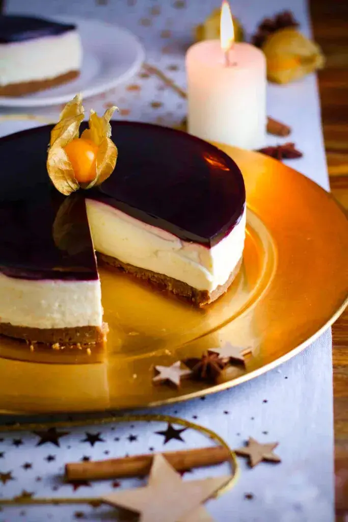 Mulled Wine Cheesecake with a spice cookie base on a dining table with a candle.