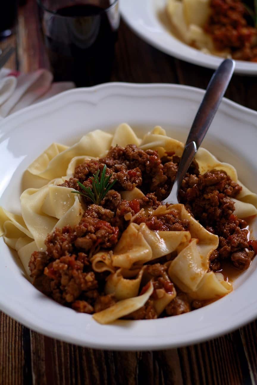 A rustic ragu made from Italian pork sausages, served over pappardelle pasta in a white bowl