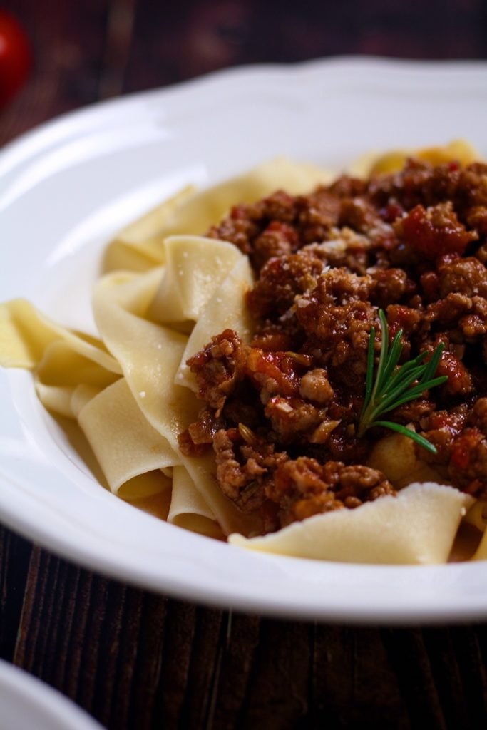 A rustic ragu made from Italian pork sausages, served over pappardelle pasta in a white bowl