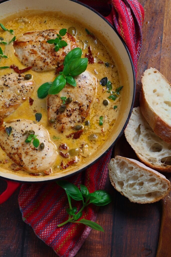 Sun-dried Tomato and Basil Chicken in an enamel pan with fresh bread on the side