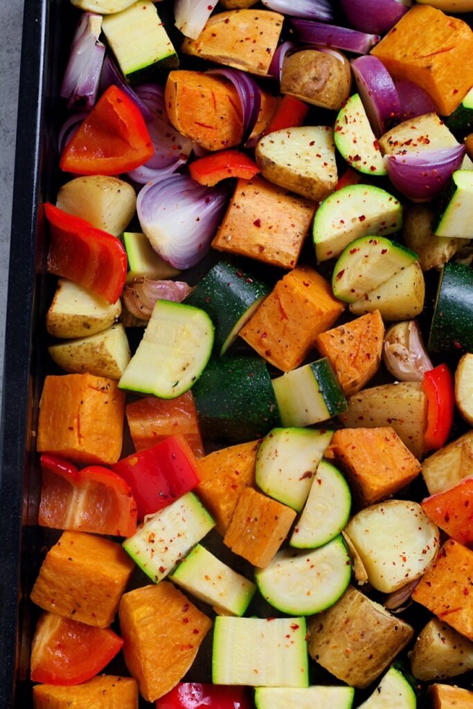Diced sweet potato, zucchini, red onion and red pepper on an oven tray