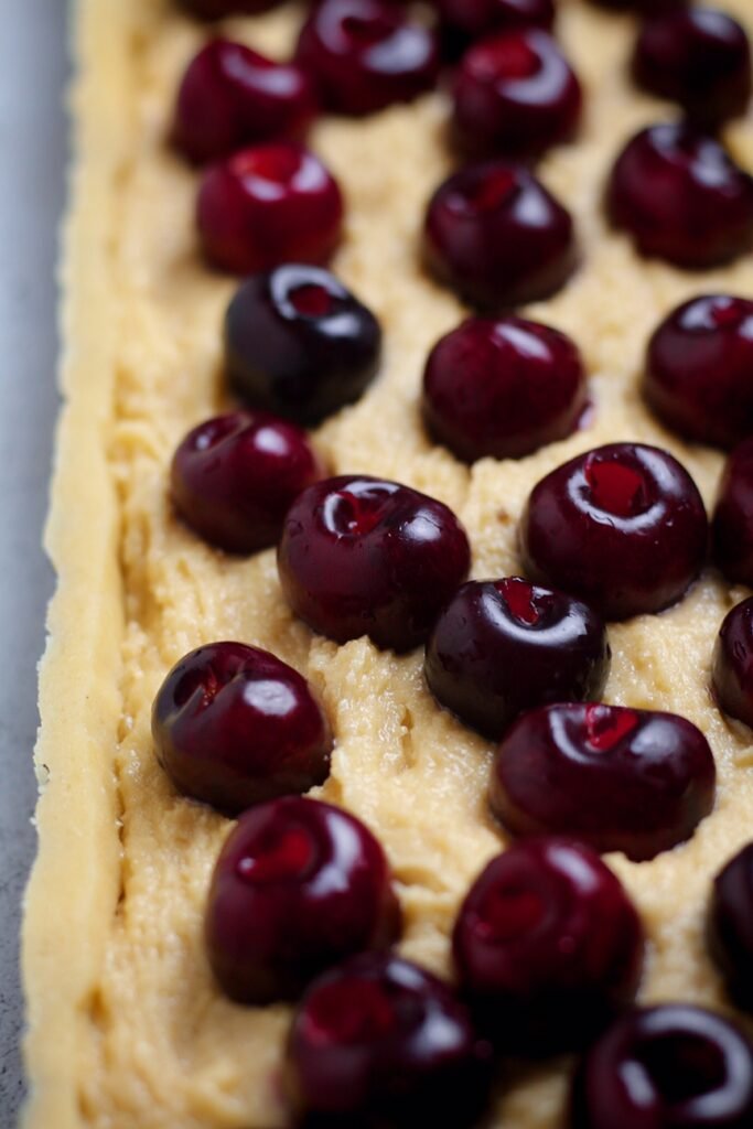 Long fluted tart pan filled with frangipane filling and cherries