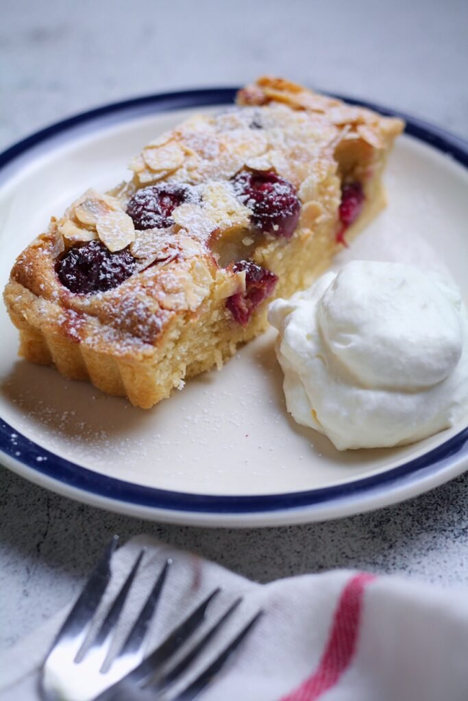  A slice of Cherry Almond Frangipane Tart on a plate with whipped cream