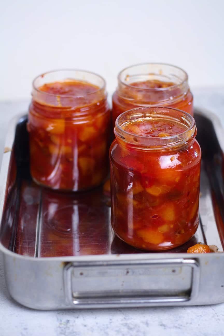 3 jars of peach and tomato chutney in a metal tray