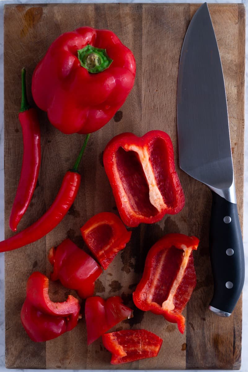 Peppers for Red Pepper Jelly on a chopping board with a chef's knife.