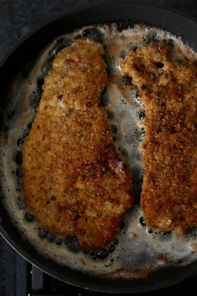 Frying Bavarian Pork Schnitzel with plenty of butter in a cast iron pan.