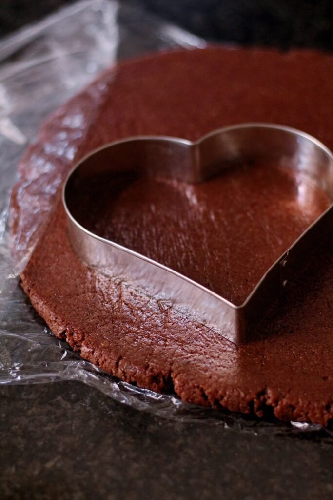 A large heart shaped cookie cutter on gingerbread dough.