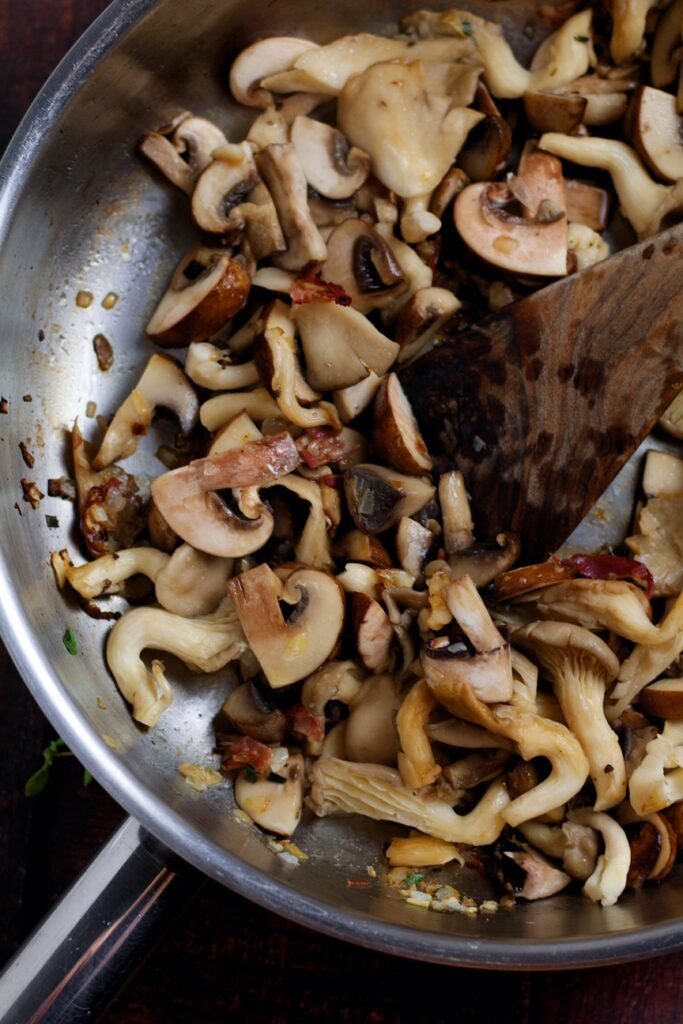 Mushrooms being sauteed in a frying pan.