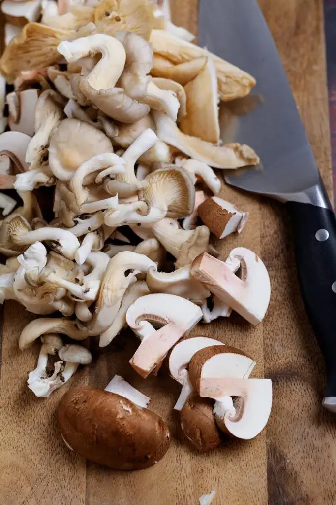Varied sliced mushrooms on a chopping board.