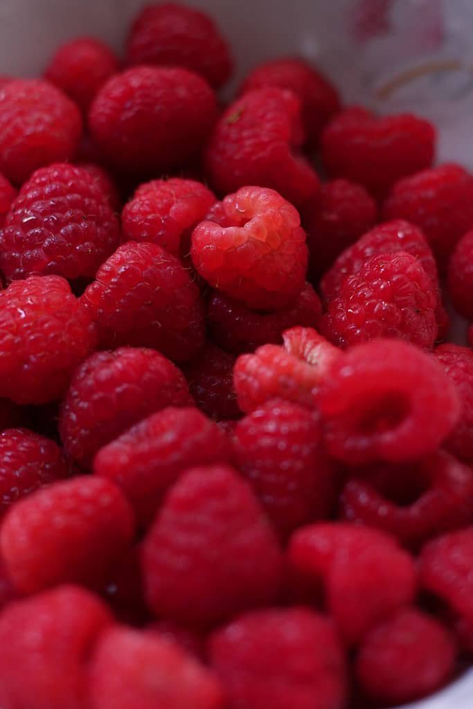 A close-up photo of fresh raspberries in a bowl.