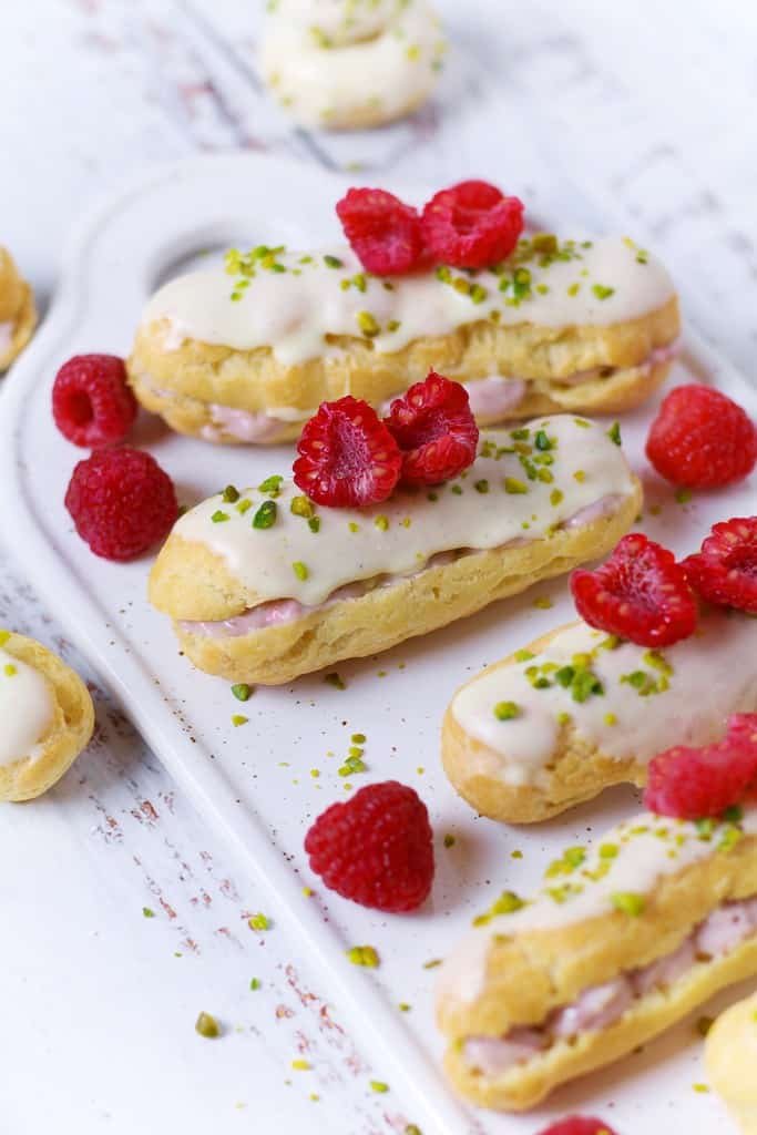 Raspberry and white chocolate eclairs decorated with pistachios and fresh raspberries.