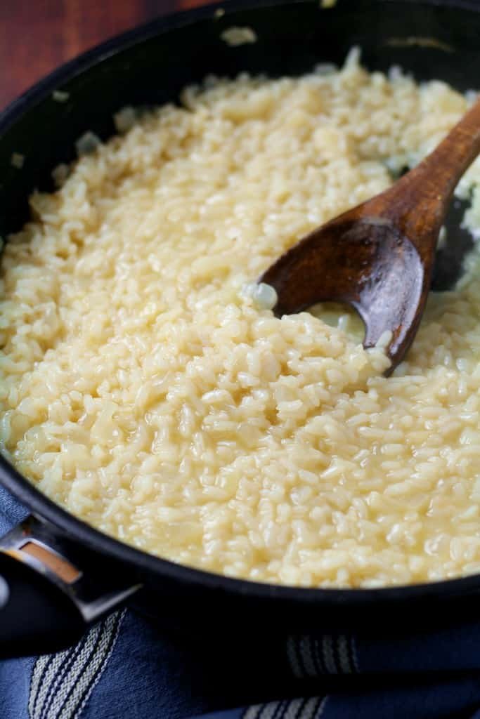 Risotto rice becoming creamier in pan.