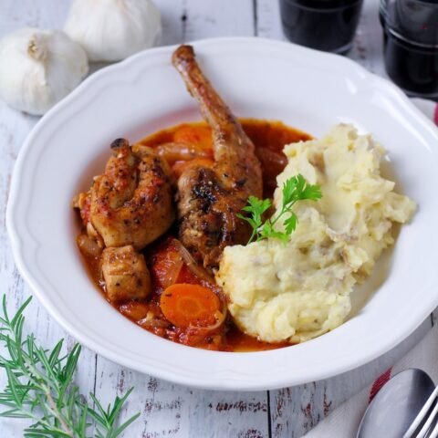 A picture of a Country-style Farmhouse Rabbit Stew served with mashed potatoes and red wine