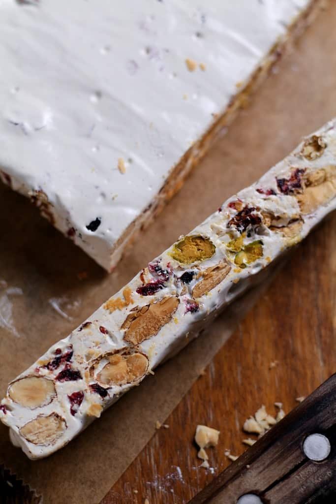 Homemade Almond and cranberry nougat sliced on a board.