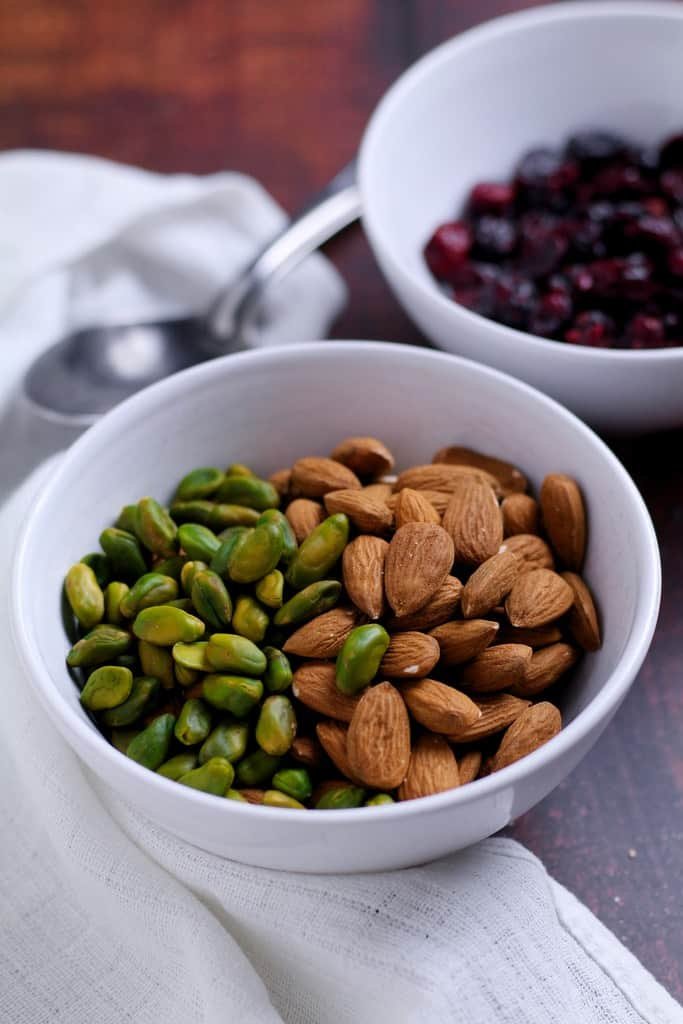 Pistachios, almonds and cranberries in bowls.