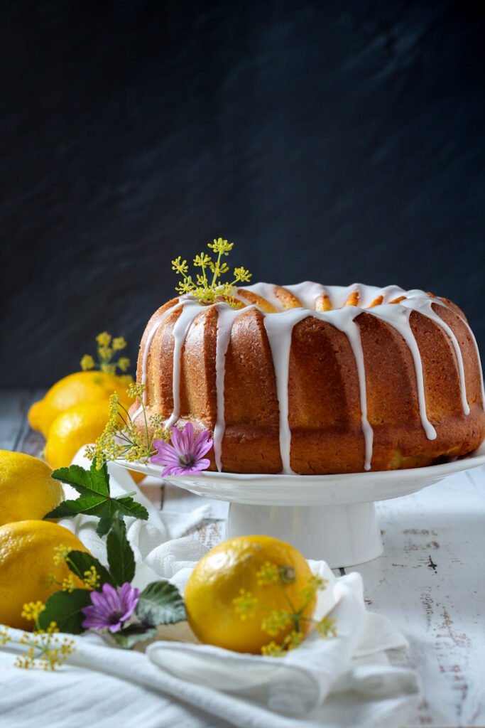 Lemon bundt cake with flowers on a cake stand.