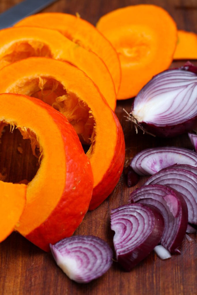 Sliced pumpkin and red onion on a chopping board