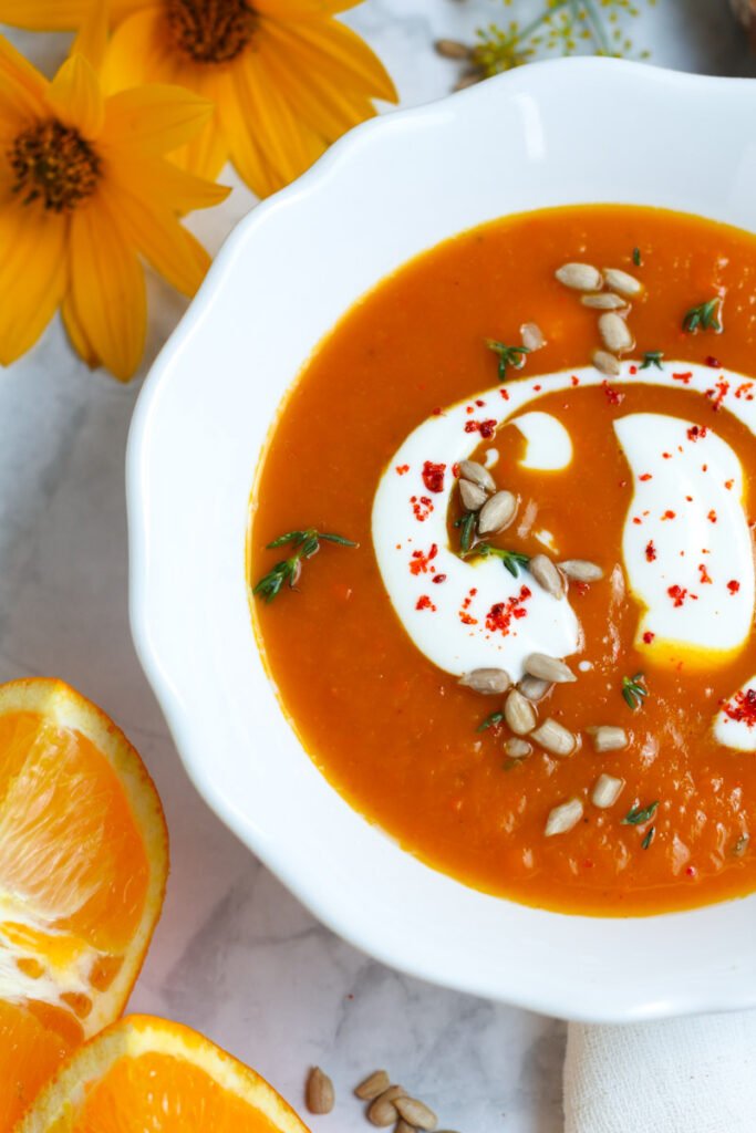 A bowl of pumpkin and ginger soup from above with a swirl of Greek yoghurt on top.