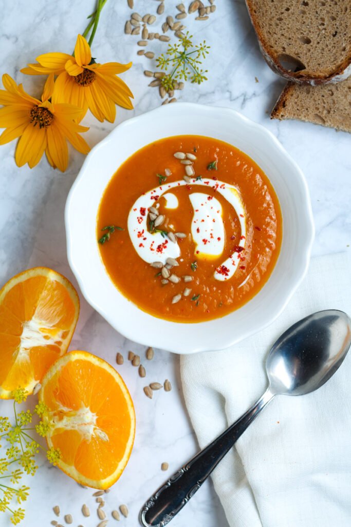 A bowl of pumpkin and ginger soup from above with a swirl of Greek yoghurt on top.