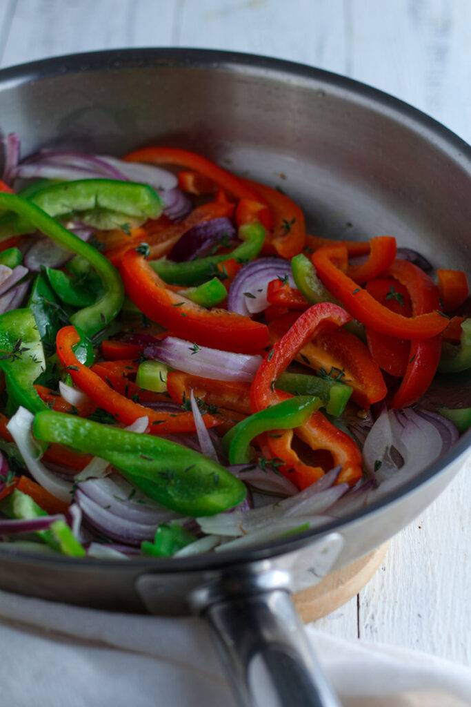 Red and green sliced peppers in a pan.