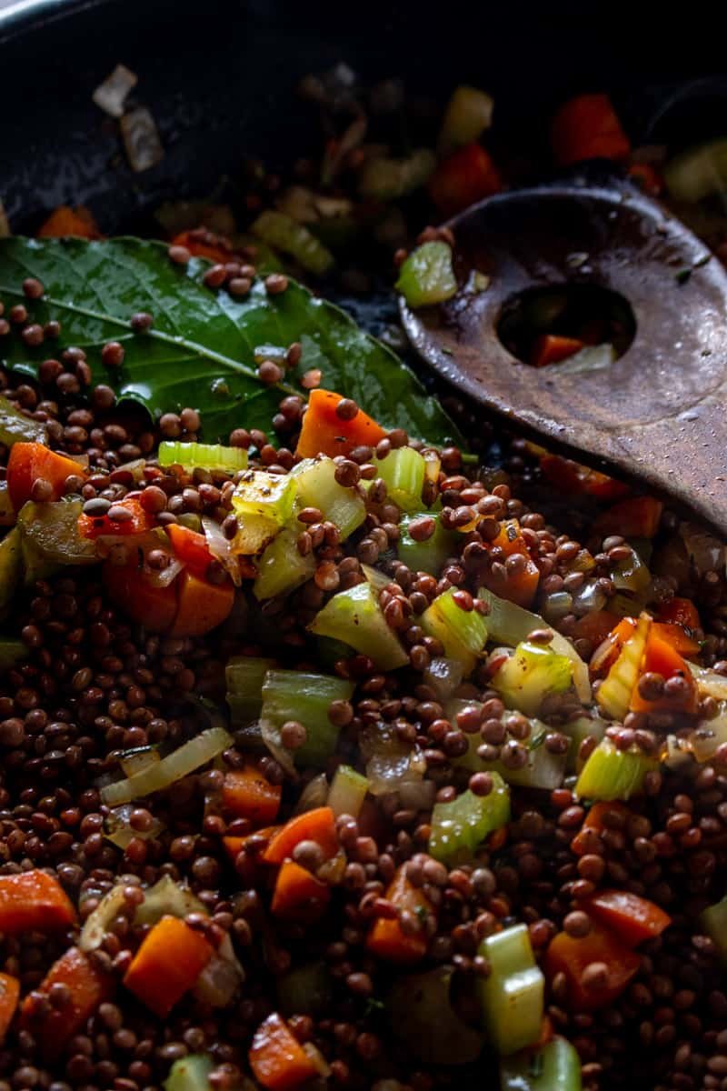 Lentils in pan with fresh bay leaf, celery and carrot.