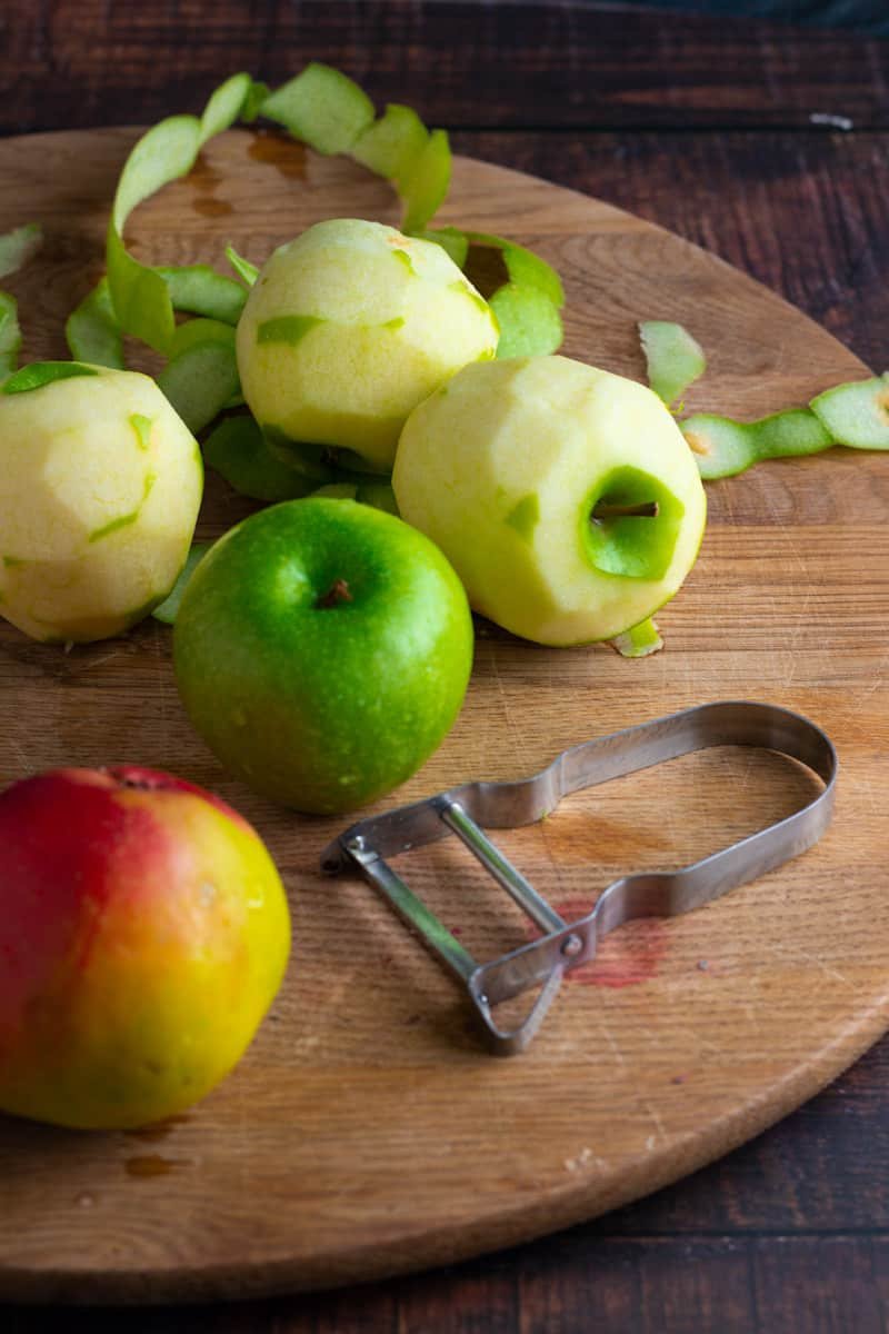 Apples for Easy German Apple Cake being peeled on a chopping board.