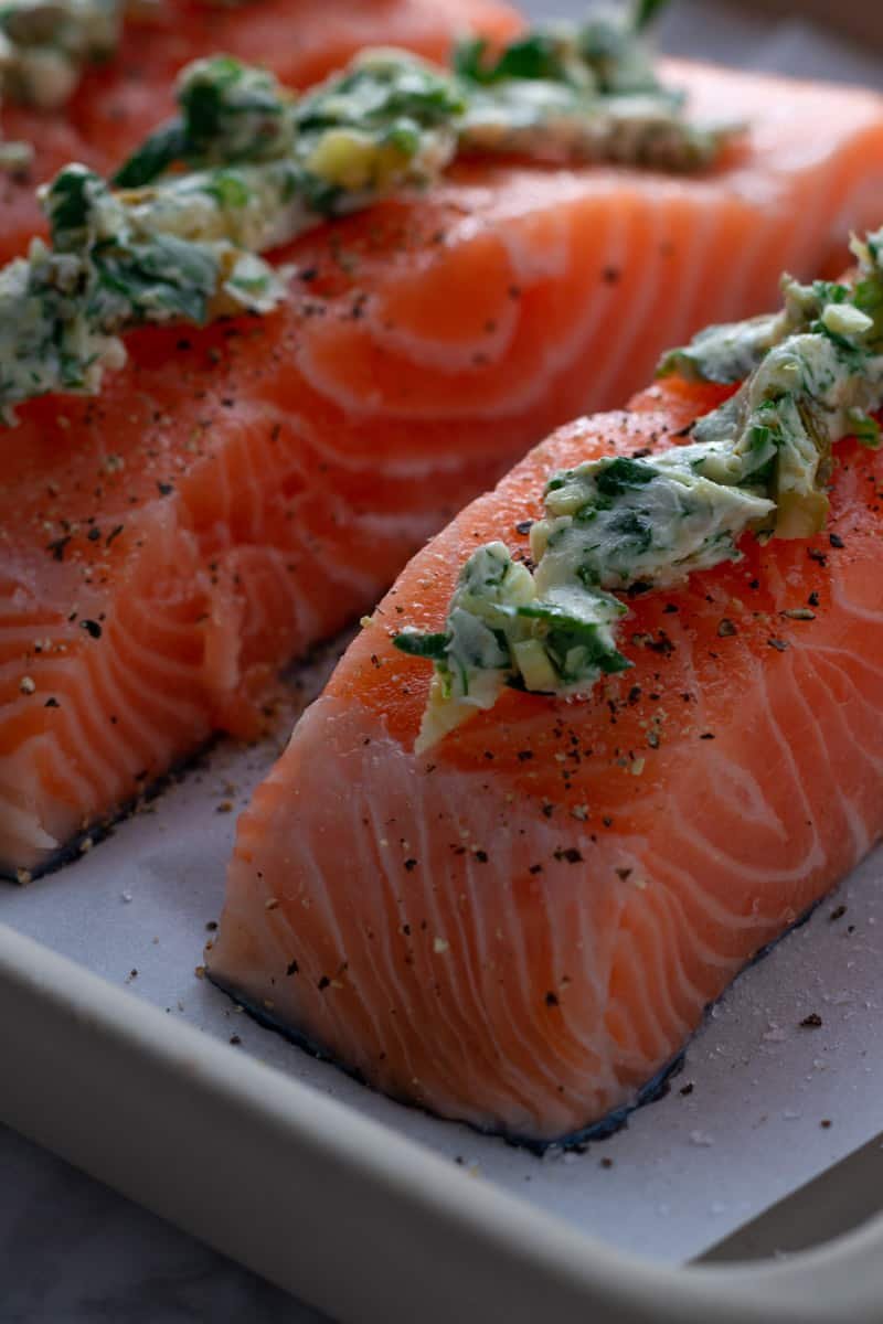 Salmon fillets on a baking tray for garlic and herb roast salmon.