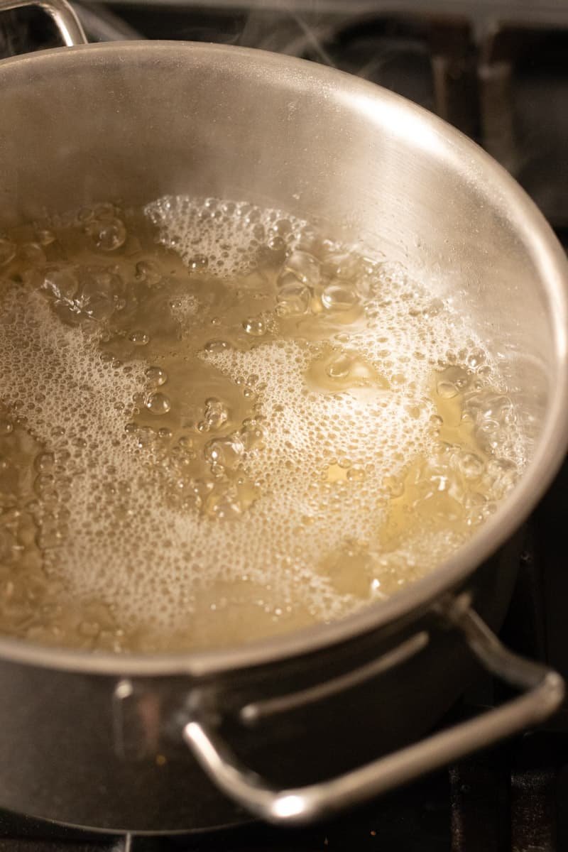 3 ingredient elderflower syrup boiling in a saucepan.