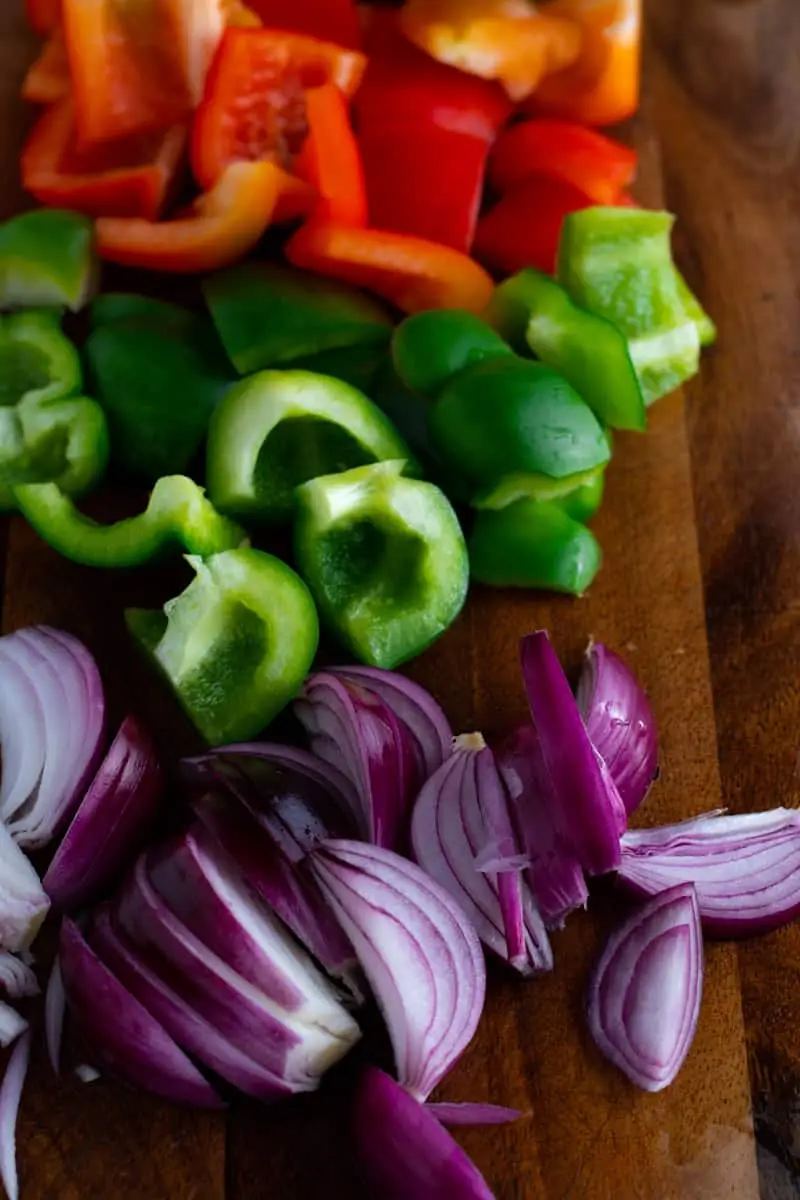 Diced bell peppers and red onion on a wooden board