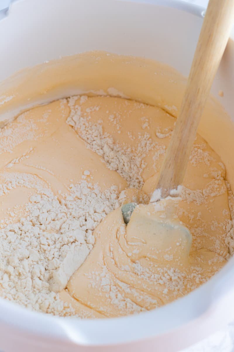 A picture of a spatula folding flour under egg and sugar mixture