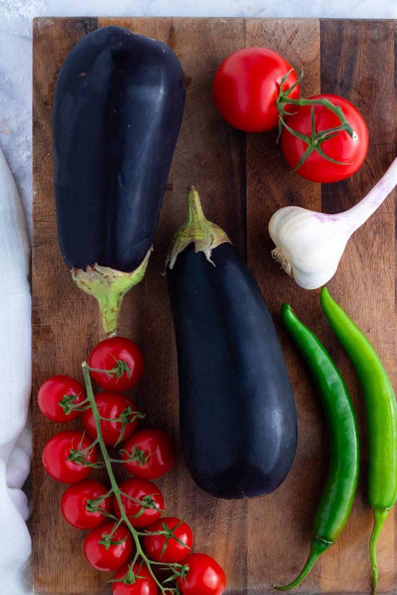 Eggplants, tomatoes, peppers and garlic on a chopping board