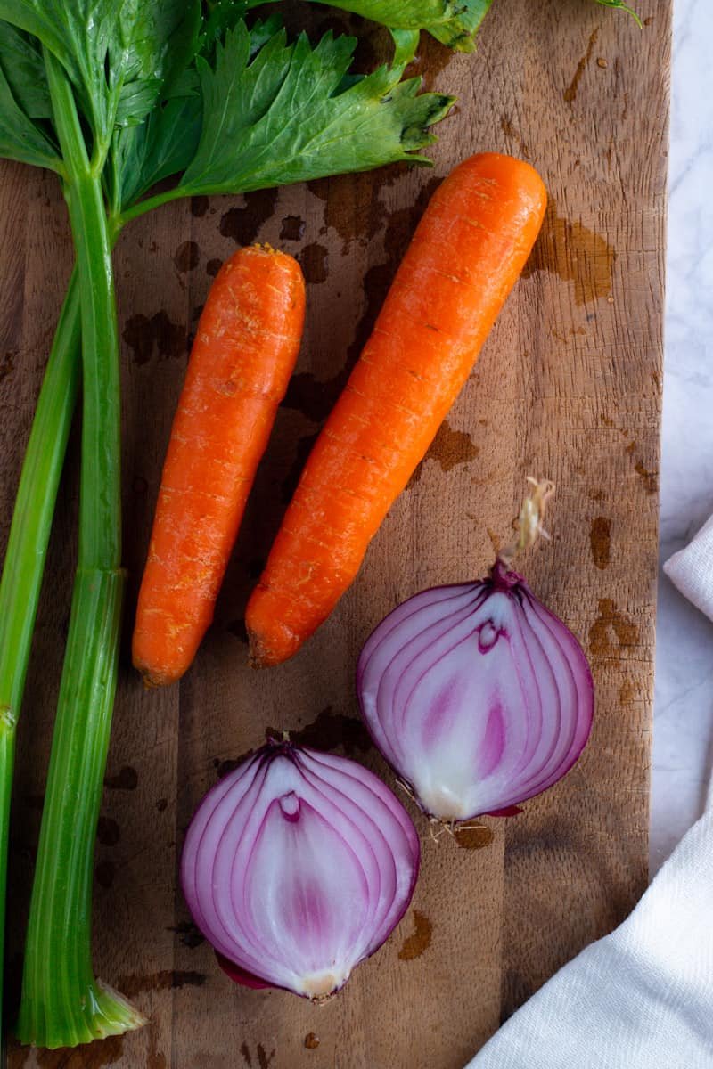 Red onions, carrots and celery on a chopping board