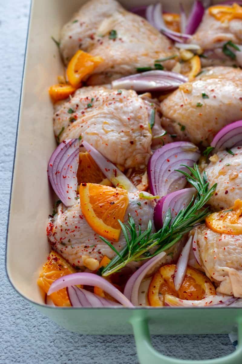 Unbaked Chicken thighs in maple orange marinade with red onions.