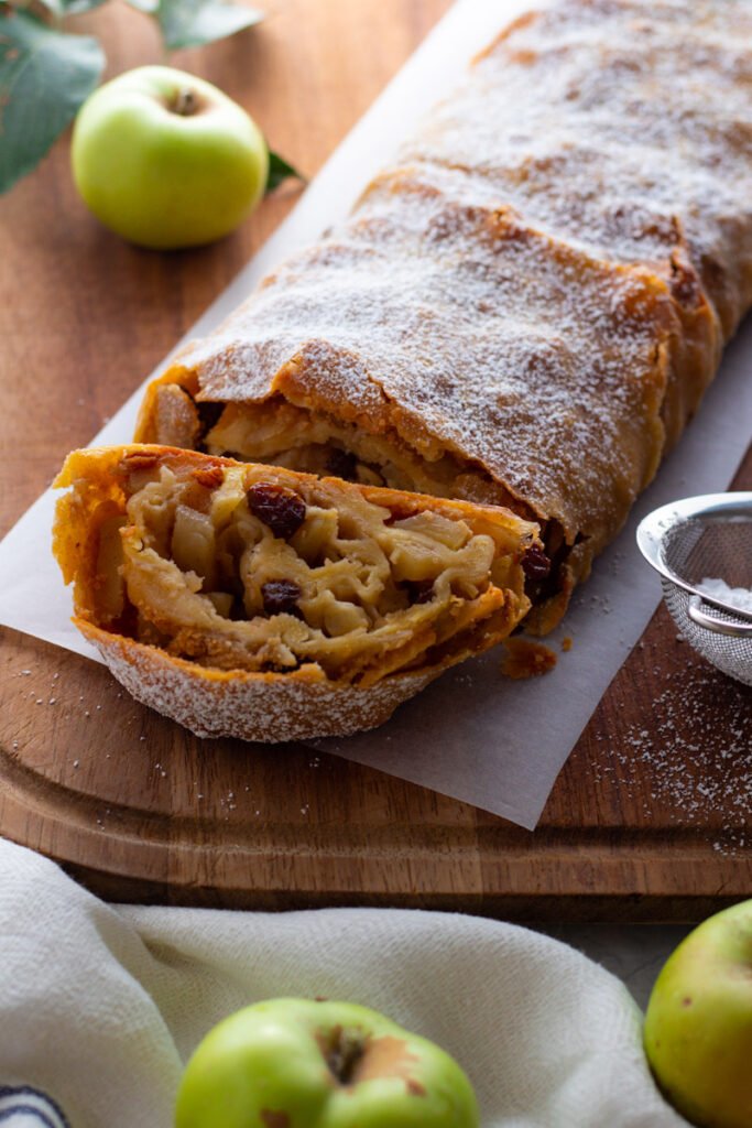 German Apple Strudel on a chopping board with fresh apples