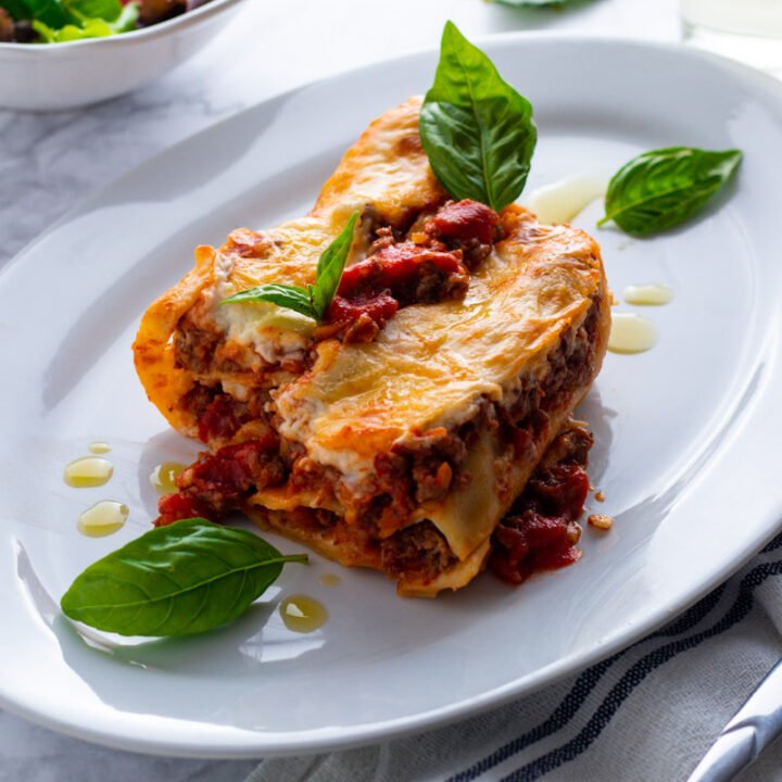Beef cannelloni pasta filled with rich beef ragu and topped with bechamel sauce on a plate