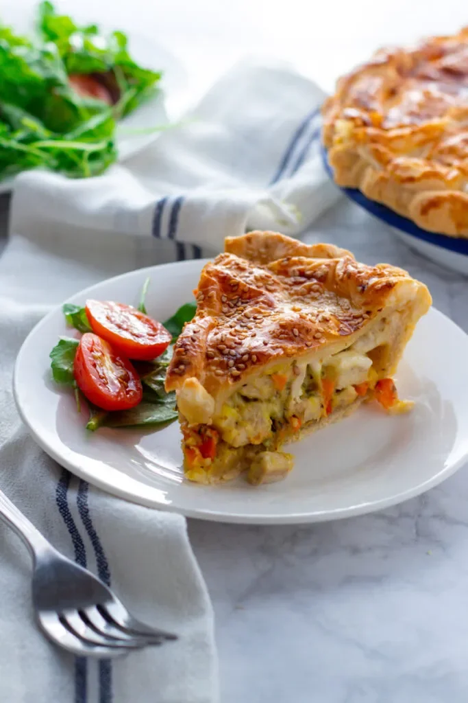 A slice of chicken pie with salad on a plate.
