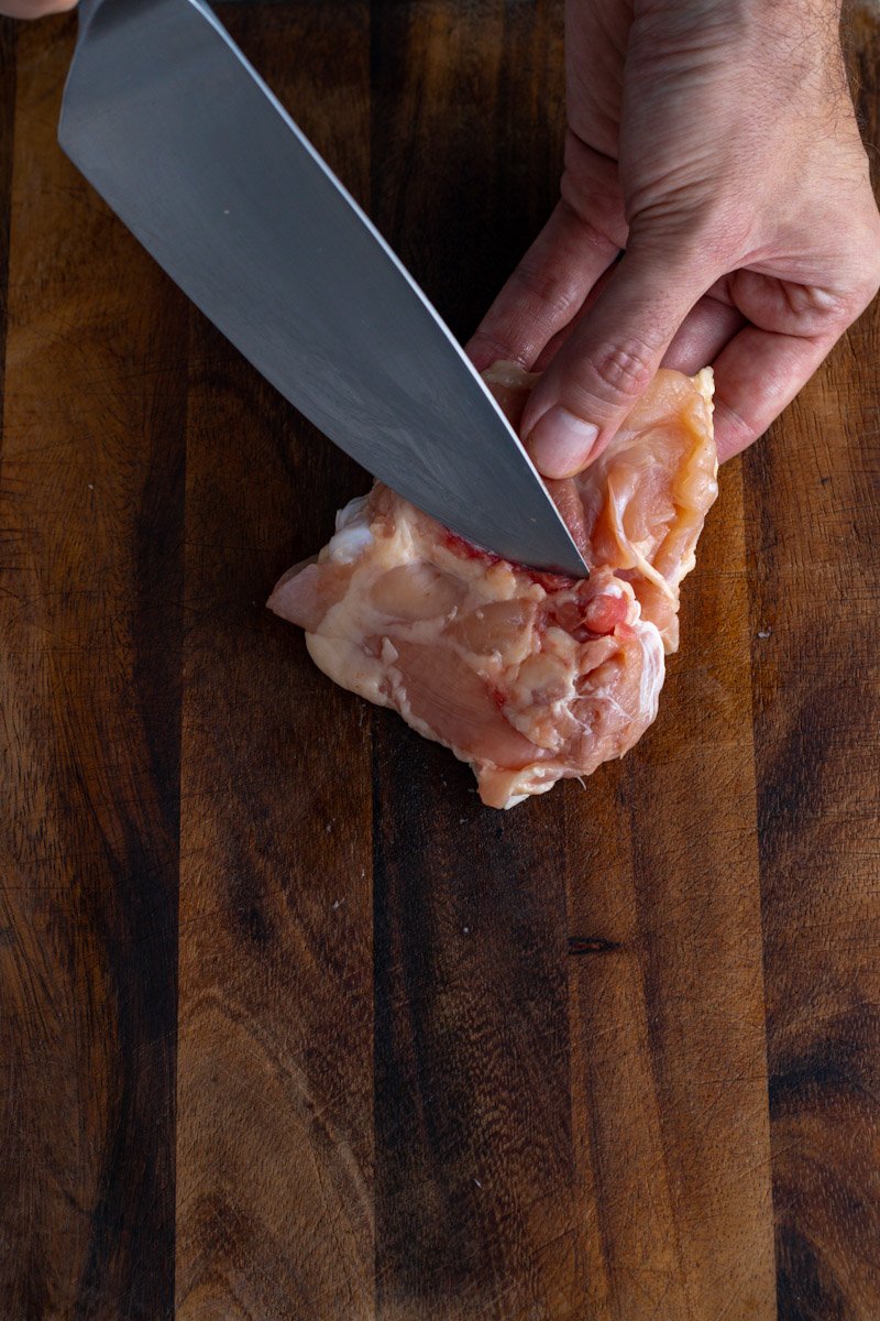 A picture of cutting down both sides of chicken thigh bone