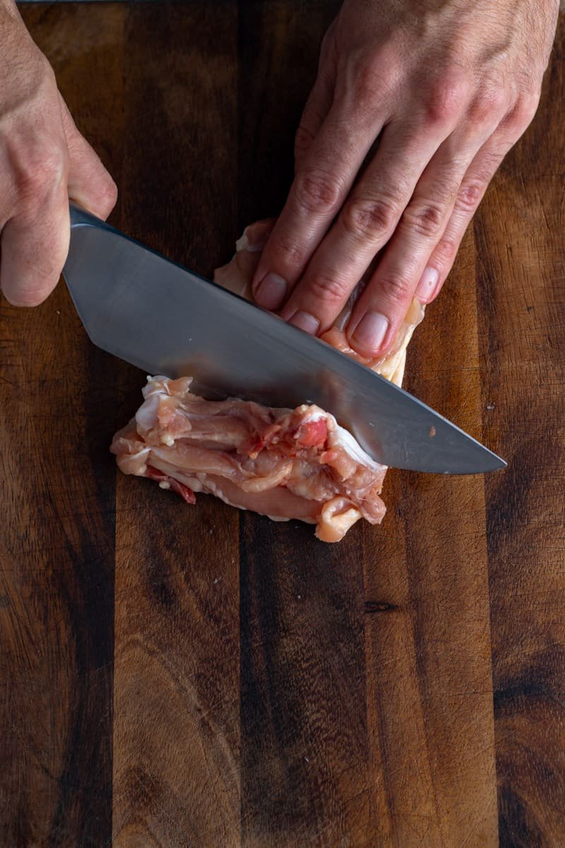 A picture of cutting underneath the chicken thigh bone