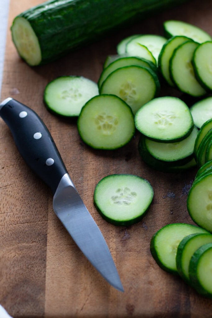 Sliced Cucumbers on a board with a knife