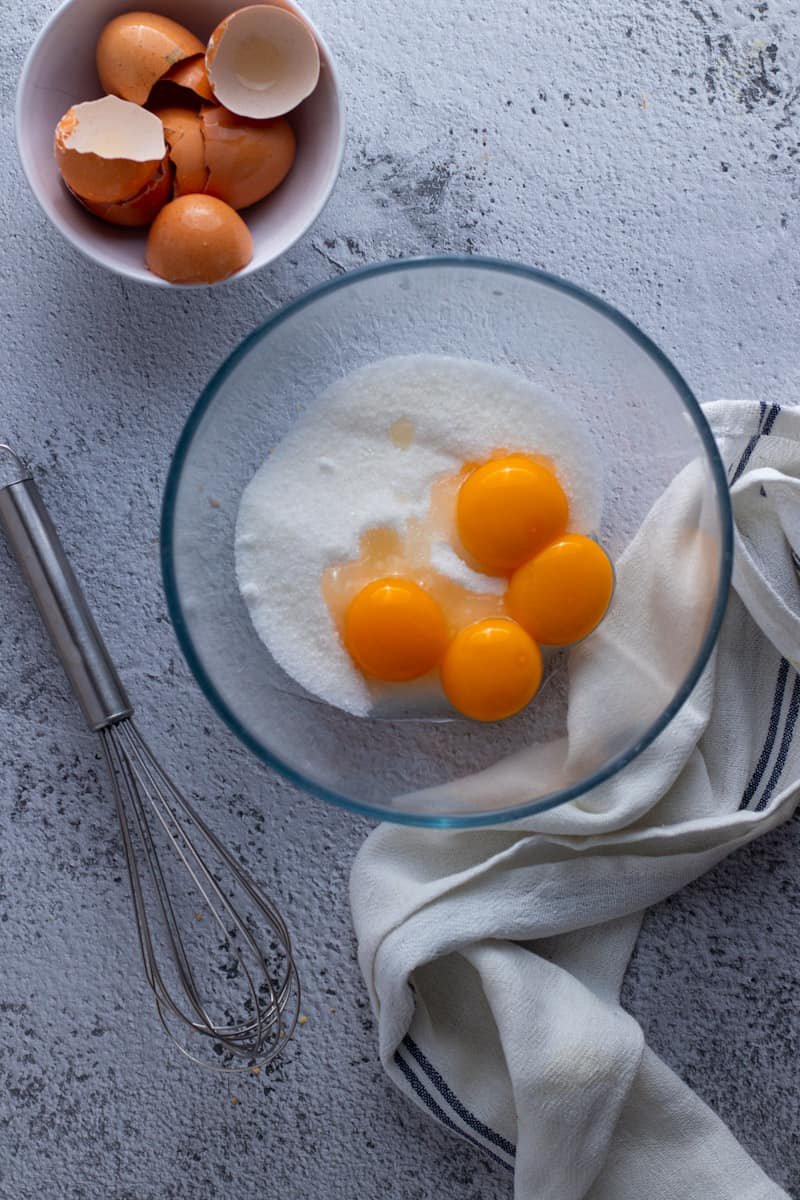 Egg yolks and sugar in a glass heat-proof bowl.