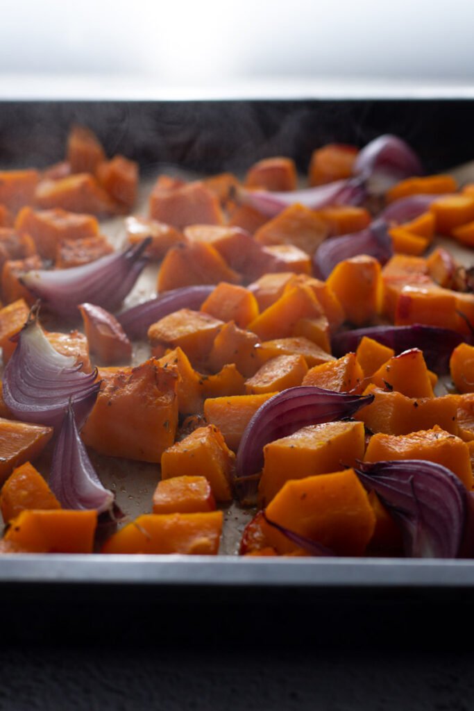 Roasted red onions and pumpkin on a baking tray.