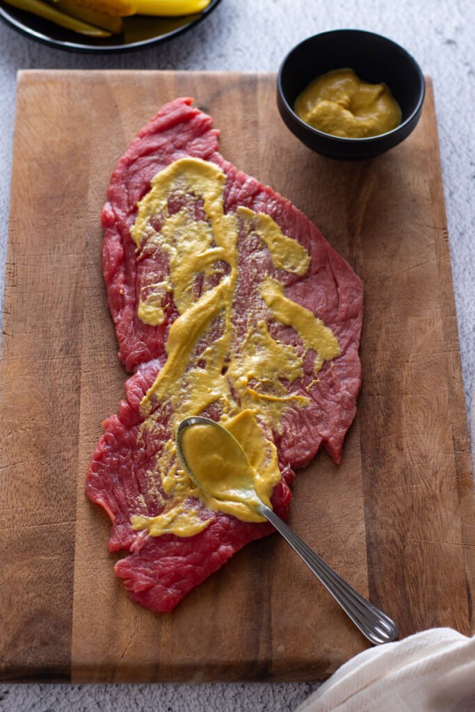 Beef steak spread with mustard for rouladen.