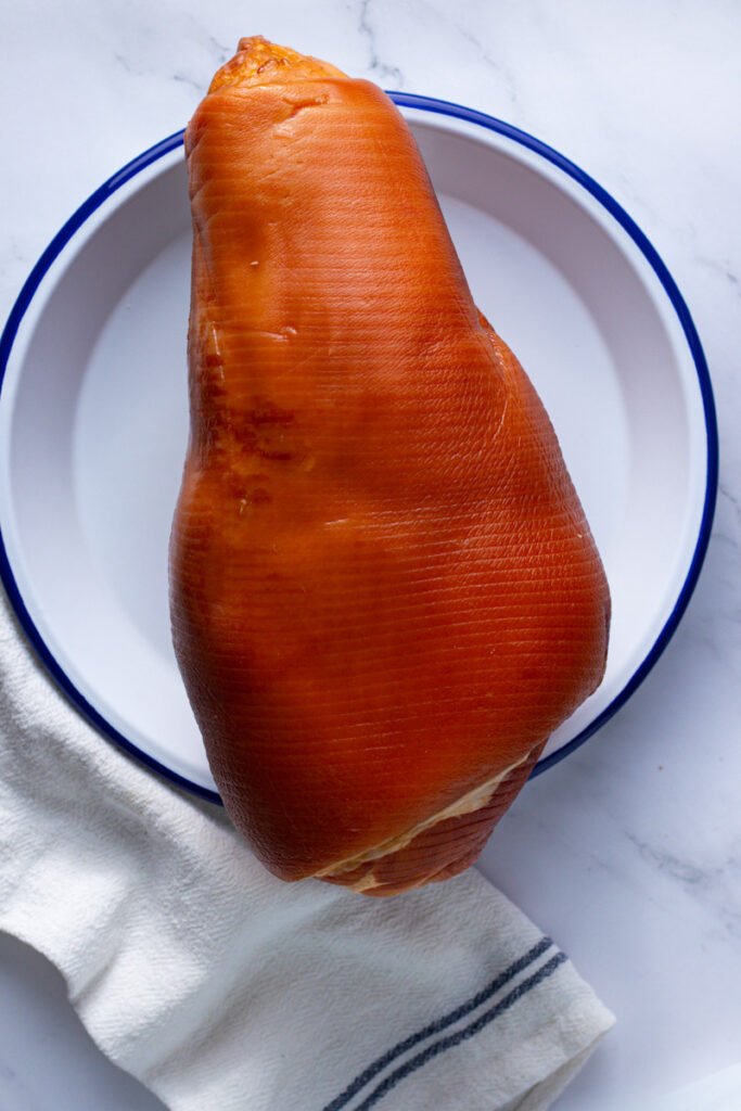 Ham with skin on on a plate.