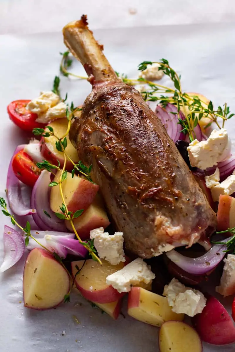 Greek Lamb Shank in parchment paper with potatoes, olives, tomatoes and onions.