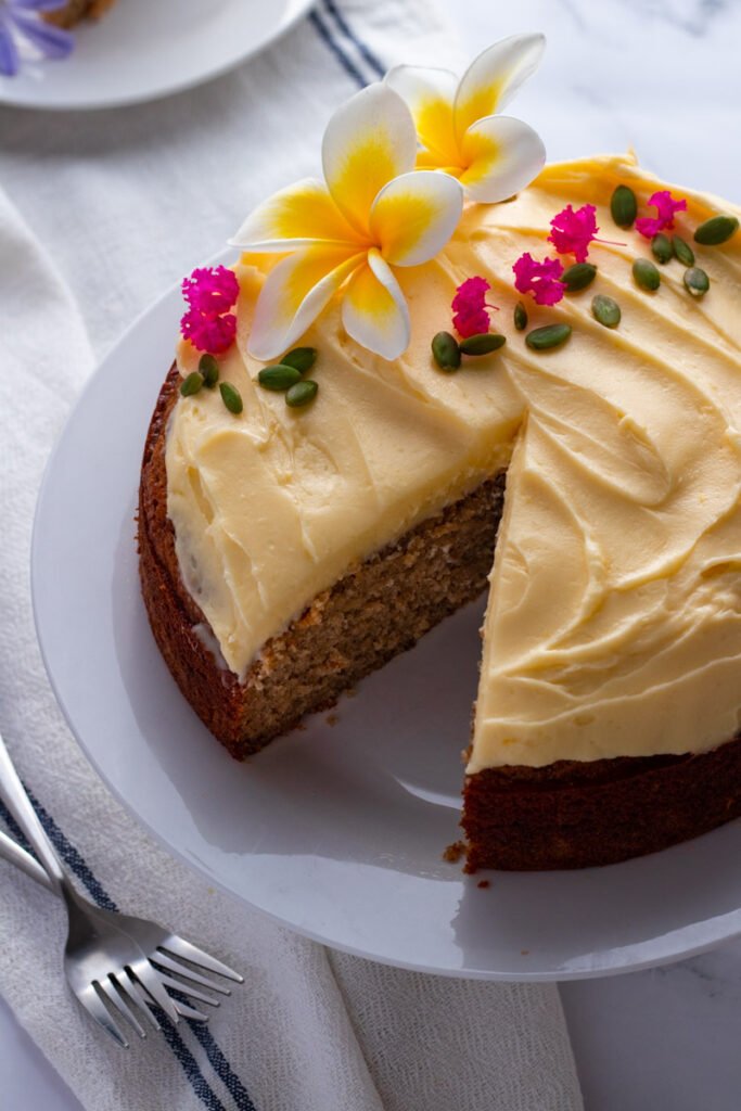 Moist banana cake with cream cheese frosting decorated with flowers.