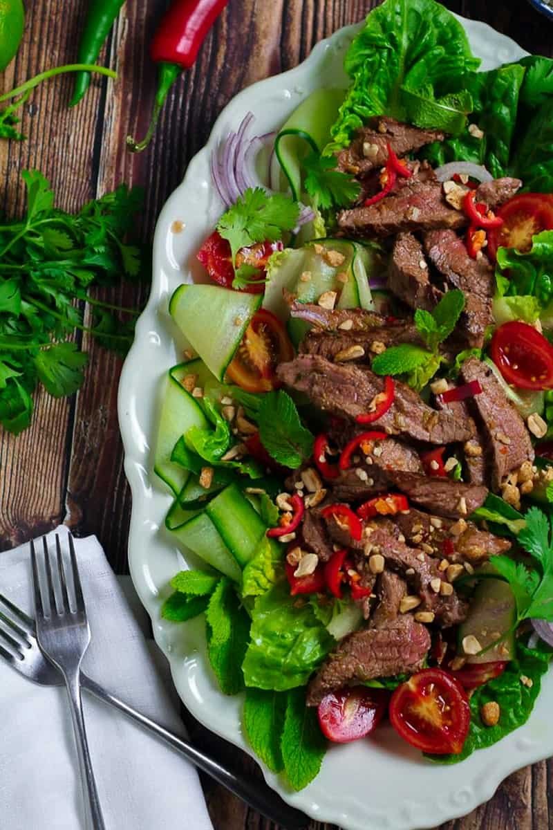 Easy Thai Beef Salad on a serving platter with beef steak, fresh herbs and vegetables.
