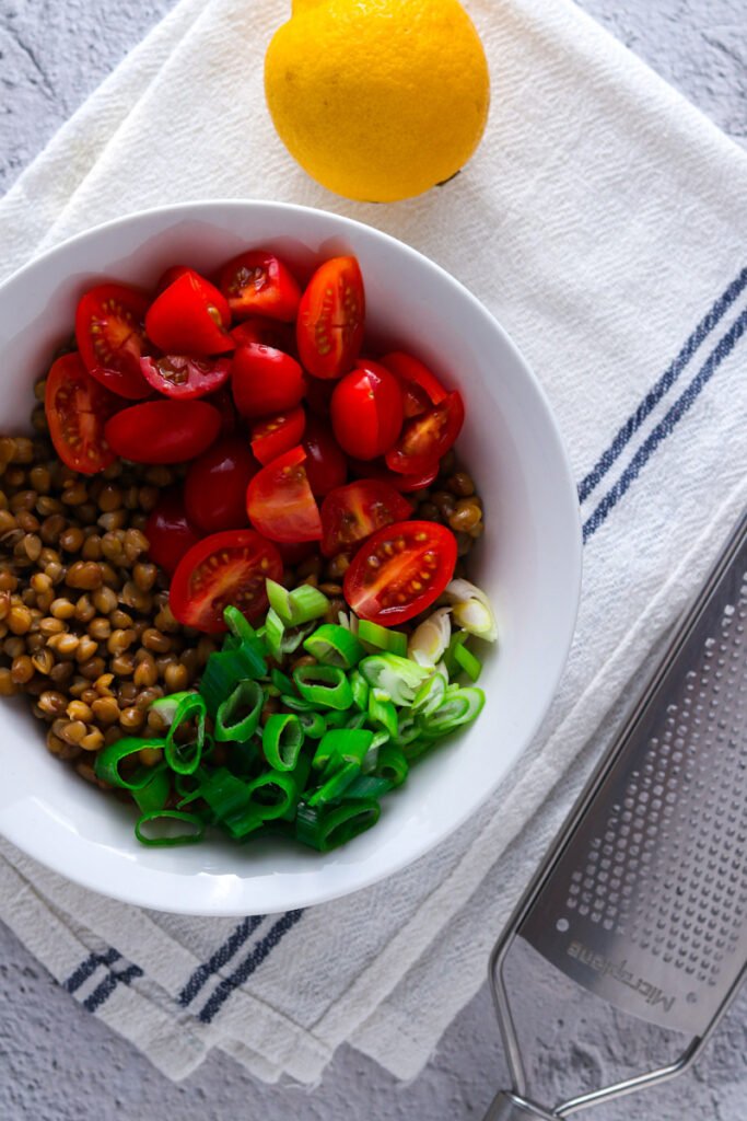 Lentils, cherry tomatoes and spring onions in a bowl.